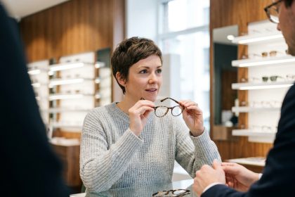 Femme en train de choisir une monture de lunettes avec l'aide d'un opticien dans une boutique moderne
