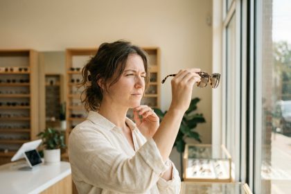 Femme examinant une paire de lunettes de soleil dans une boutique d'optique avant de l'acheter