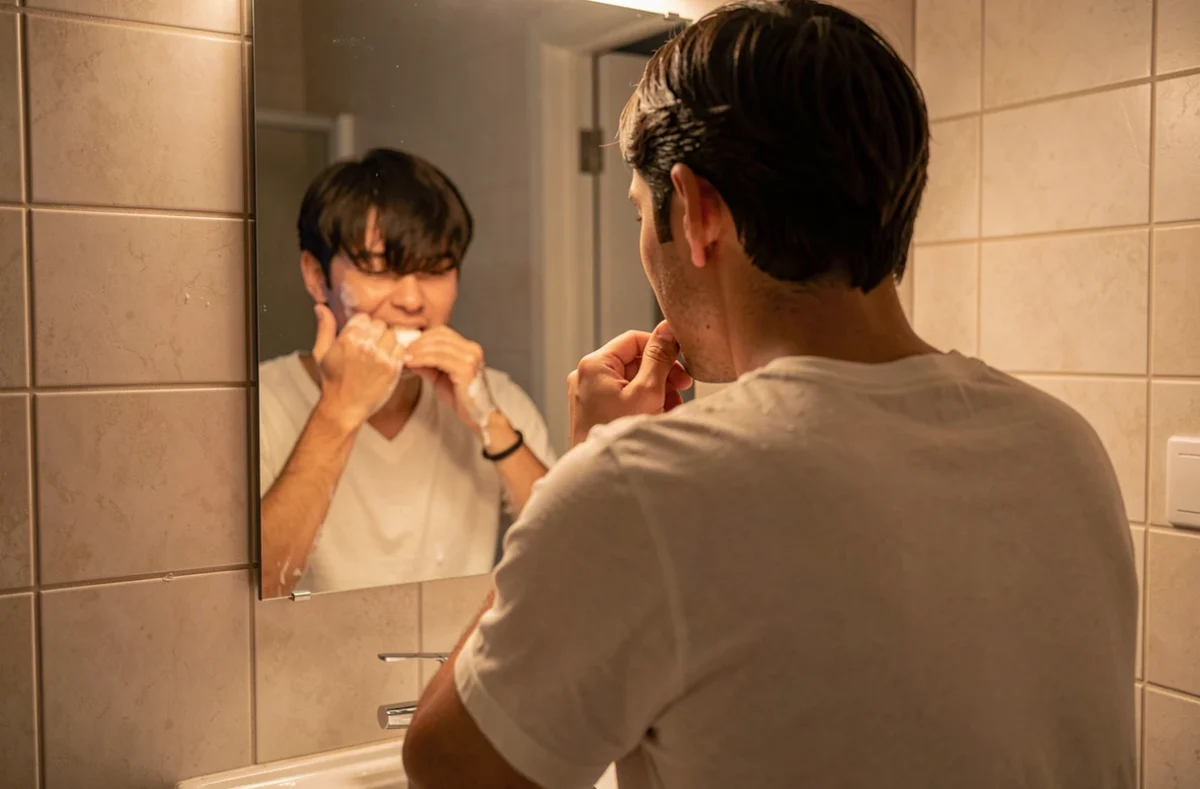 Personne qui se brosse les dents devant un miroir
